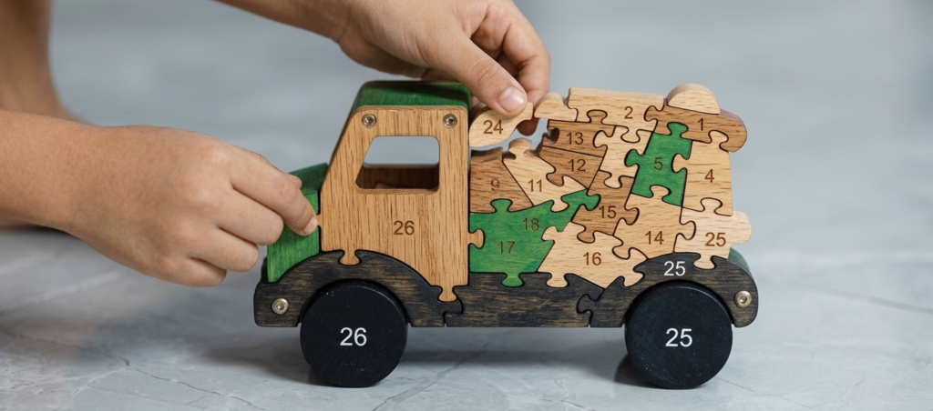 Enfant assemblant un puzzle de camion numéroté.